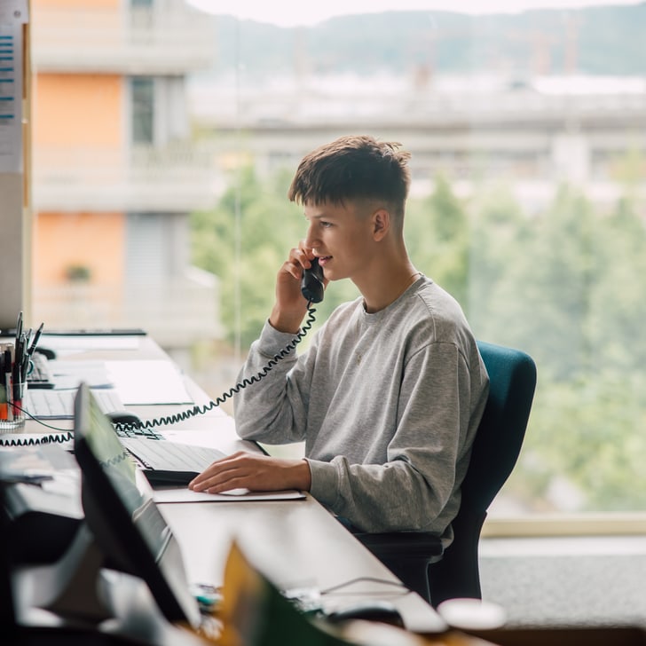 Person am Schreibtisch telefoniert im Büro.