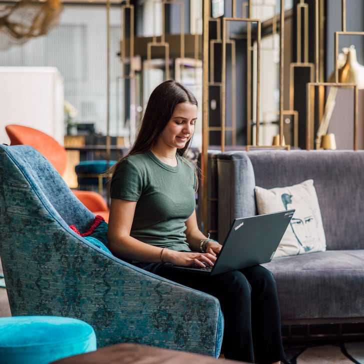 Frau mit Laptop in modernem Wohnzimmer.