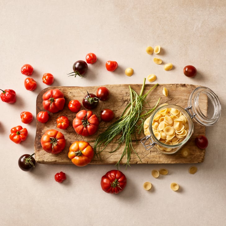 Holzbrett mit verschiedenen Tomaten, Kräutern und Glasnudeln.