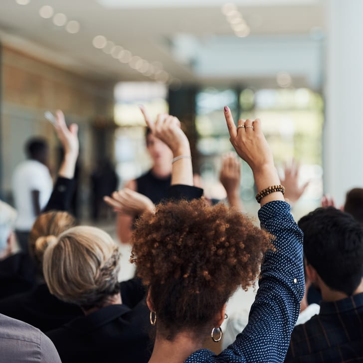 Menschen heben im Seminarraum die Hände",