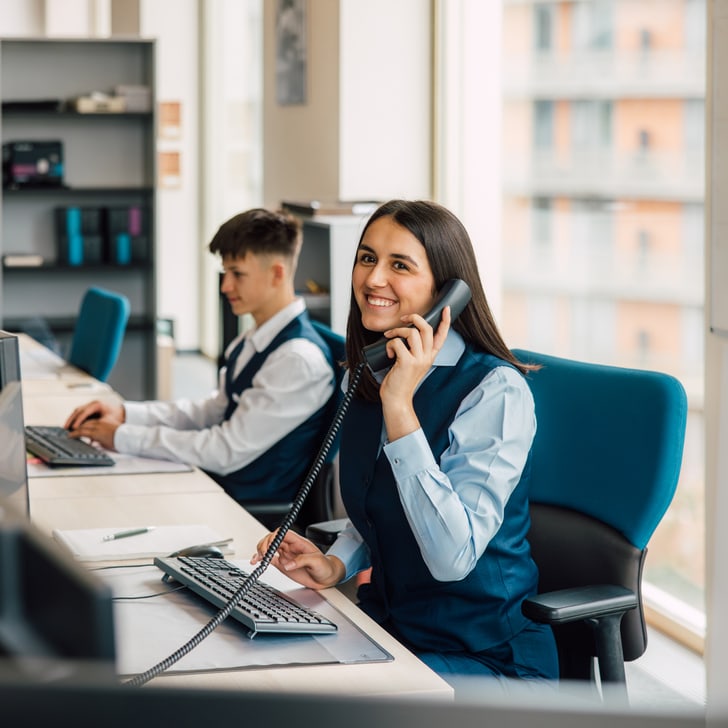 Büromitarbeiterin telefoniert am Schreibtisch.