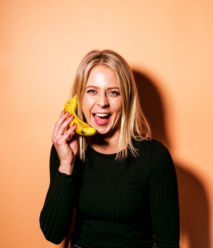 Frau in schwarzem Oberteil hält eine Banane ans Ohr.