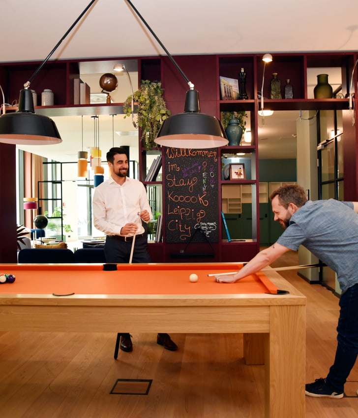 Zwei Männer spielen Billard in einem stilvollen Raum.