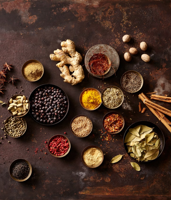 Verschiedene Gewürze auf braunem Hintergrund arrangiert.
