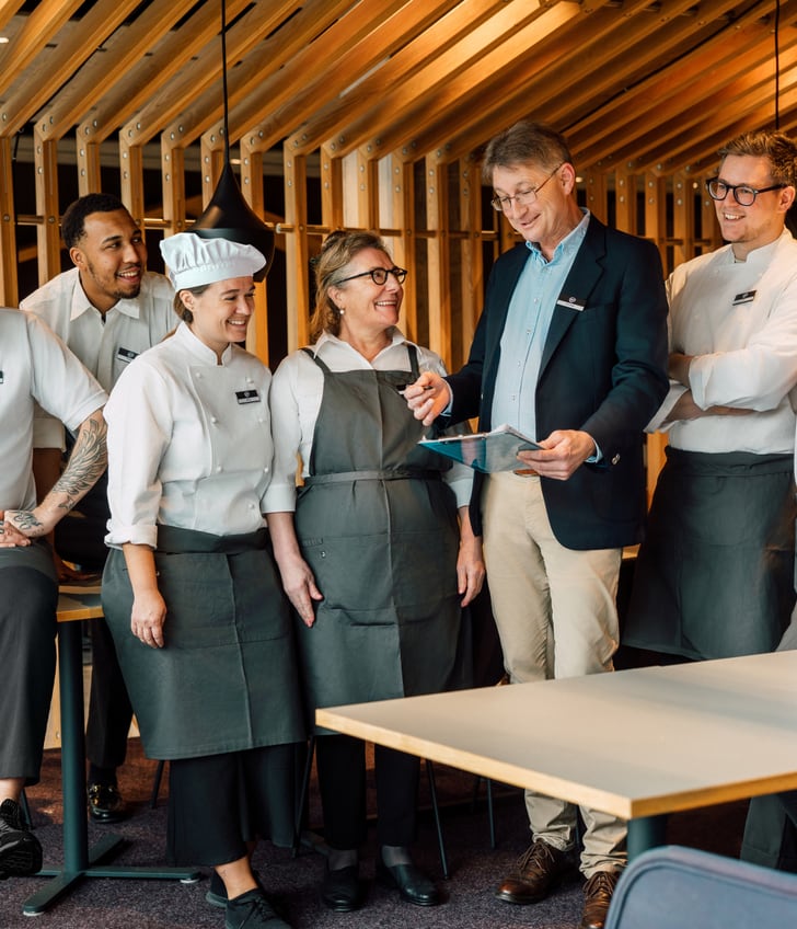 Gruppe von Restaurantmitarbeitern in Uniform lächelnd mit Manager.
