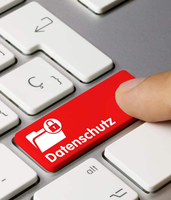 Finger drückt auf eine Computertaste mit der Aufschrift 'Datenschutz'.
