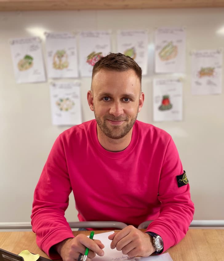 Mitarbeiter sitzend mit Stift in der Hand und Blatt Papier und Laptop auf dem Tisch 