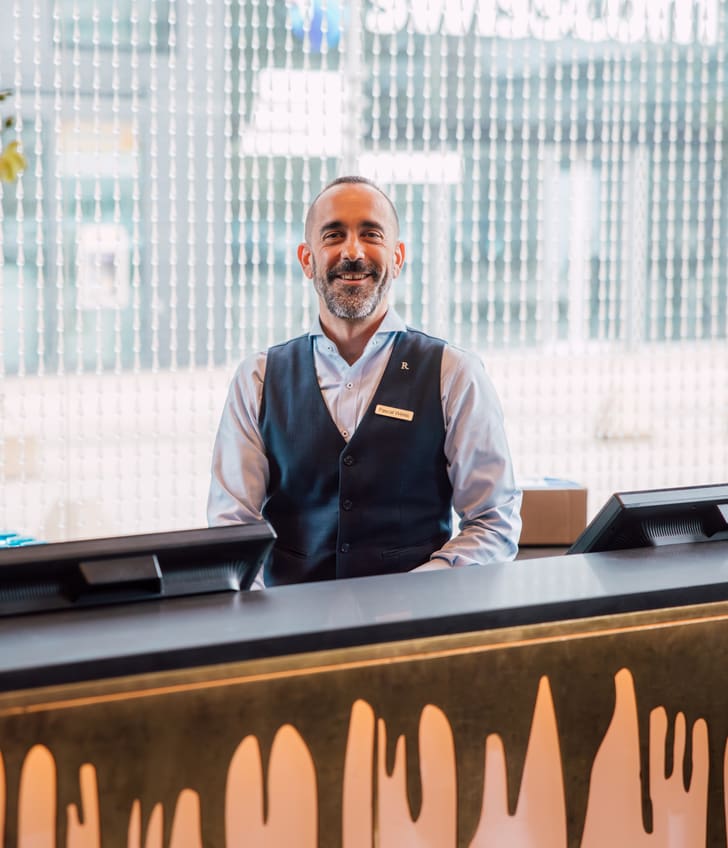 Hotelangestellter an der Rezeption mit Lächeln.