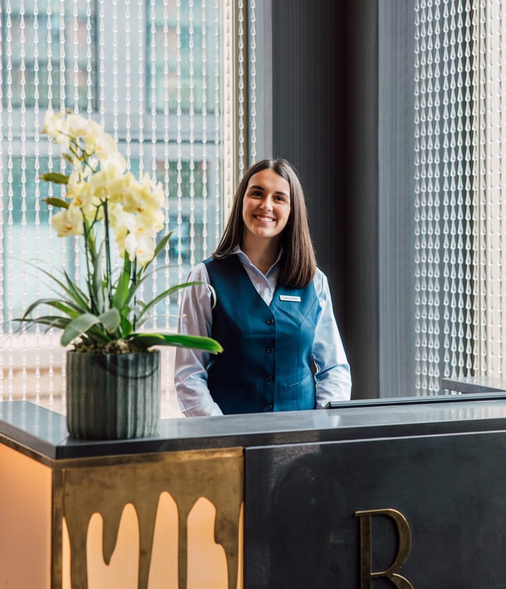 Rezeptionistin an einem Empfangstresen mit Blume.