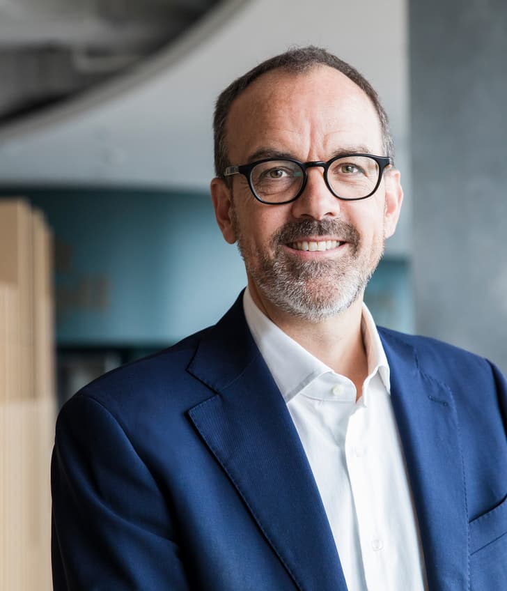 Mann im Anzug und Brille, lächelt.