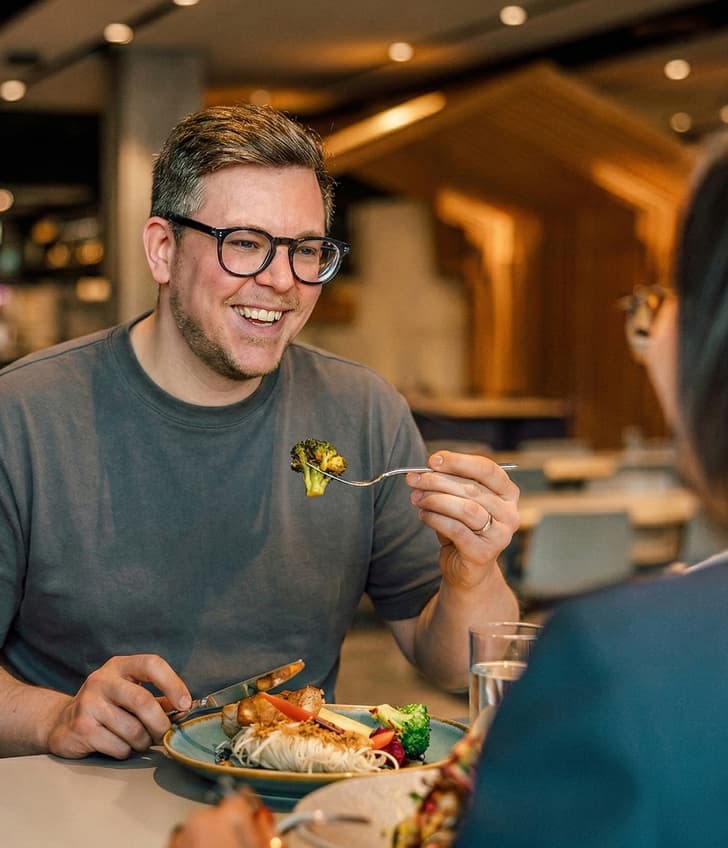 Mann lächelt beim Essen in einem Restaurant.