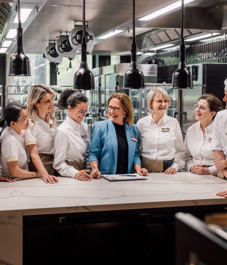 Küchenpersonal versammelt sich um einen Tisch in einer modernen Küche.