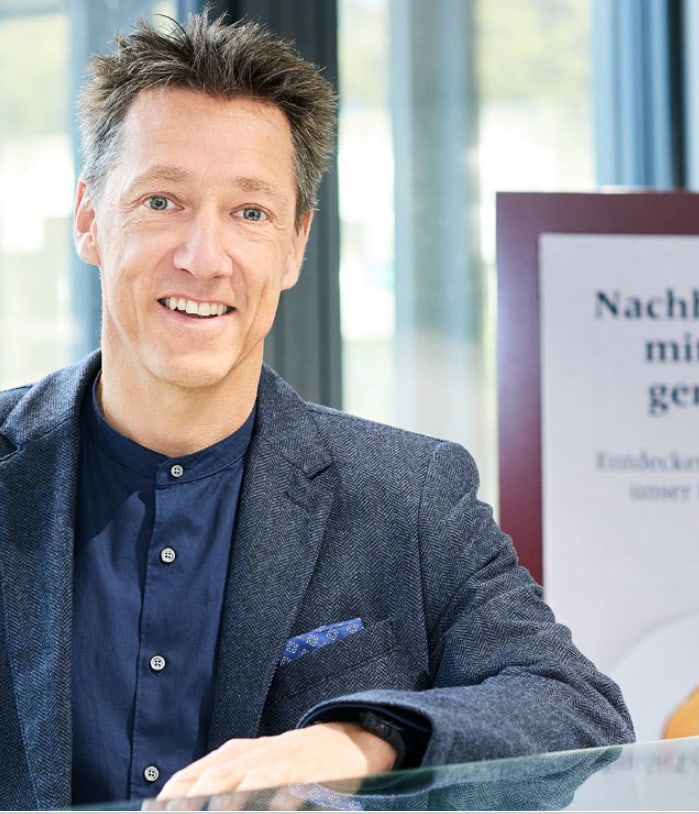 Mann lächelt neben Schild über Nachhaltigkeit.