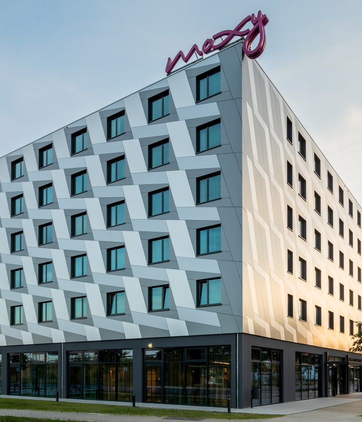 Bâtiment d'hôtel moderne avec façade géométrique au coucher du soleil.