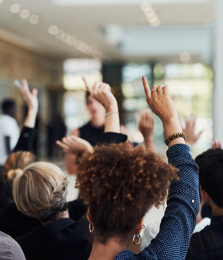 Menschen heben Hände bei einer Versammlung.