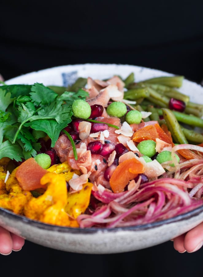 Eine Frau hält eine Bowl mit gesunden und frischen Zutaten in den Händen.