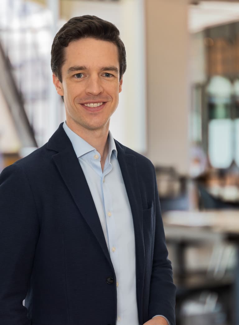 Mann in Anzug lächelnd in modernem Büro.