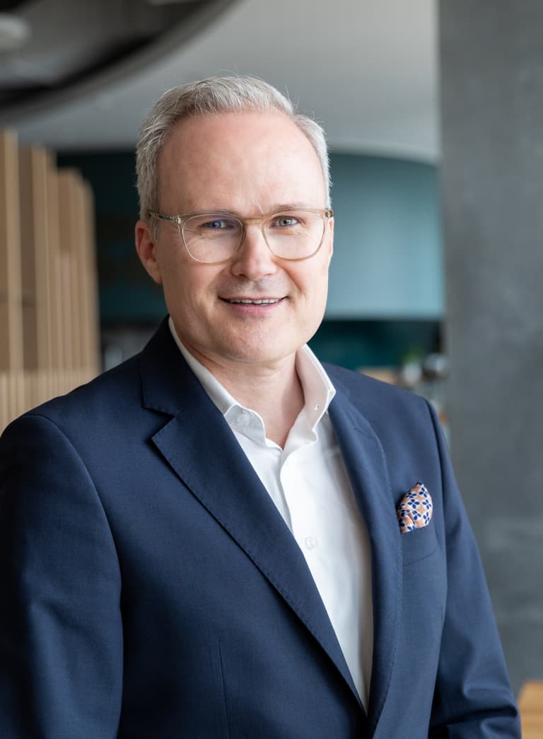 Mann in Anzug lächelt in modernem Büro.