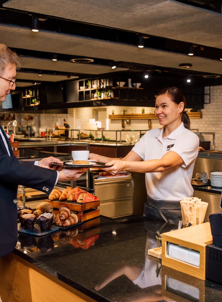 Kunde und Barista in einem Café mit Gebäck.