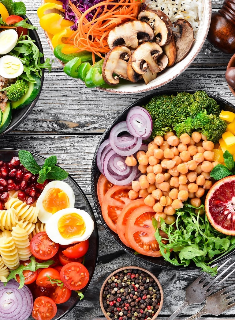 Verschiedene bunte Gerichte auf einem Holztisch.