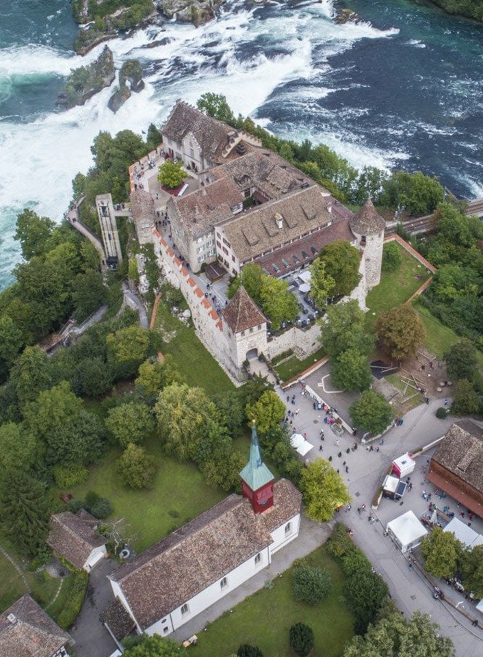 Luftaufnahme eines Schlosses neben einem Fluss und Wasserfall.