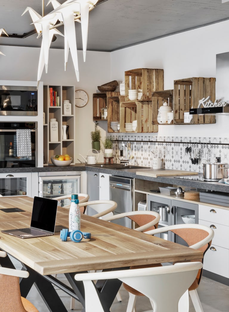 Stay Kooook Bern Gemeinschaftsküche mit langem Tisch 8 Stühlen und Küche im Hintergrund.