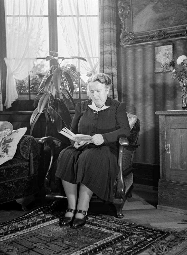 Historisches Bild von der Gründerin der SV Else Züblin-Spiller, die auf einem Stuhl im Wohnzimmer sitzt und ein Buch liest.
