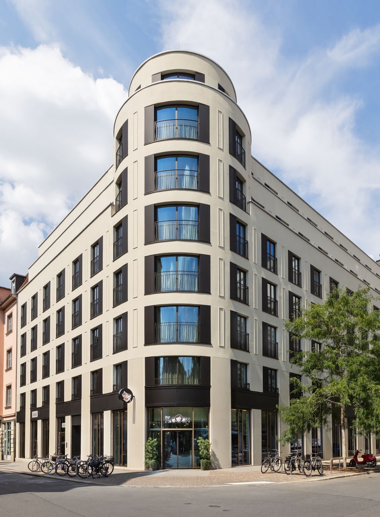 Moderne Gebäude mit runder Ecke auf einer Strasse bei Tag.",