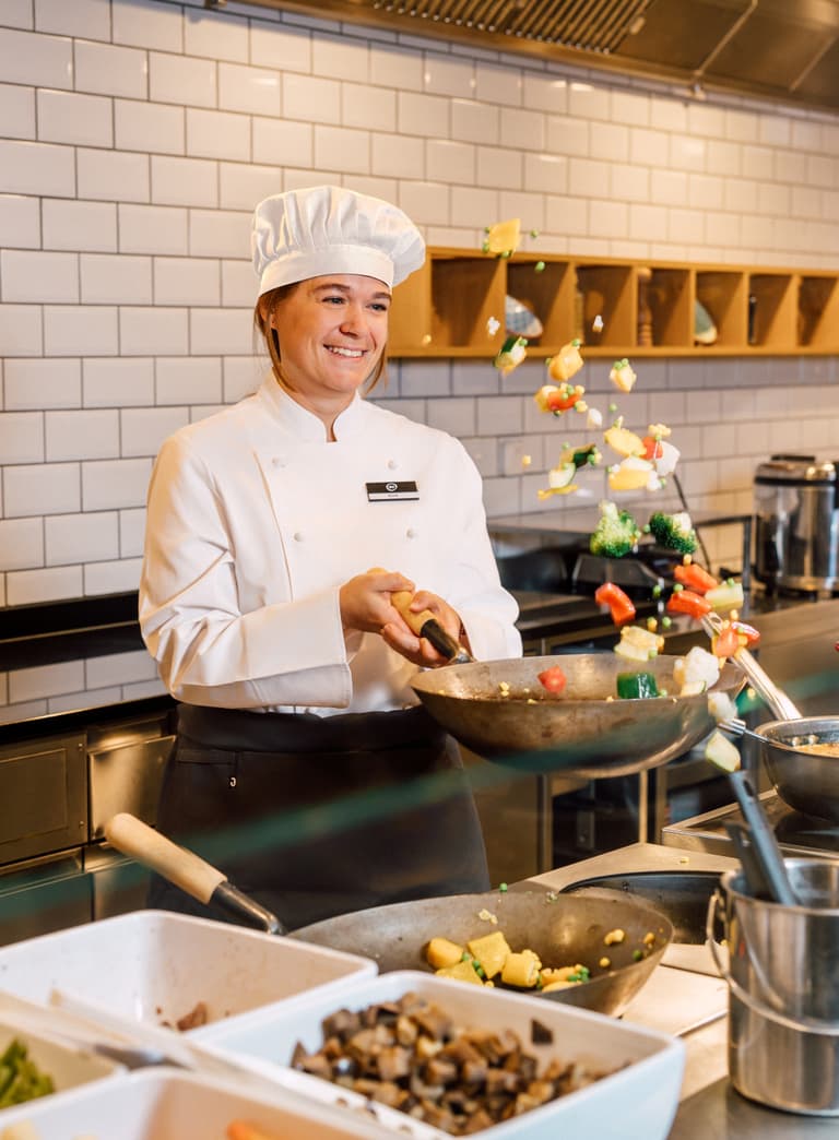 Koch jongliert Gemüse in Küche.