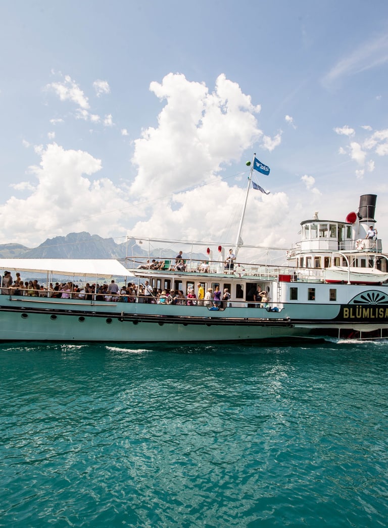 Schiff fährt auf dem See bei schönem Wetter und viele Personen sind auf dem Schiff zu sehen.