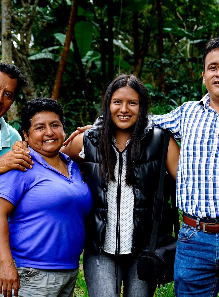 Vier Menschen lächelnd draussen in grüner Umgebung.