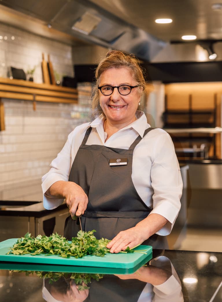 Köchin schneidet Kräuter in moderner Küche.