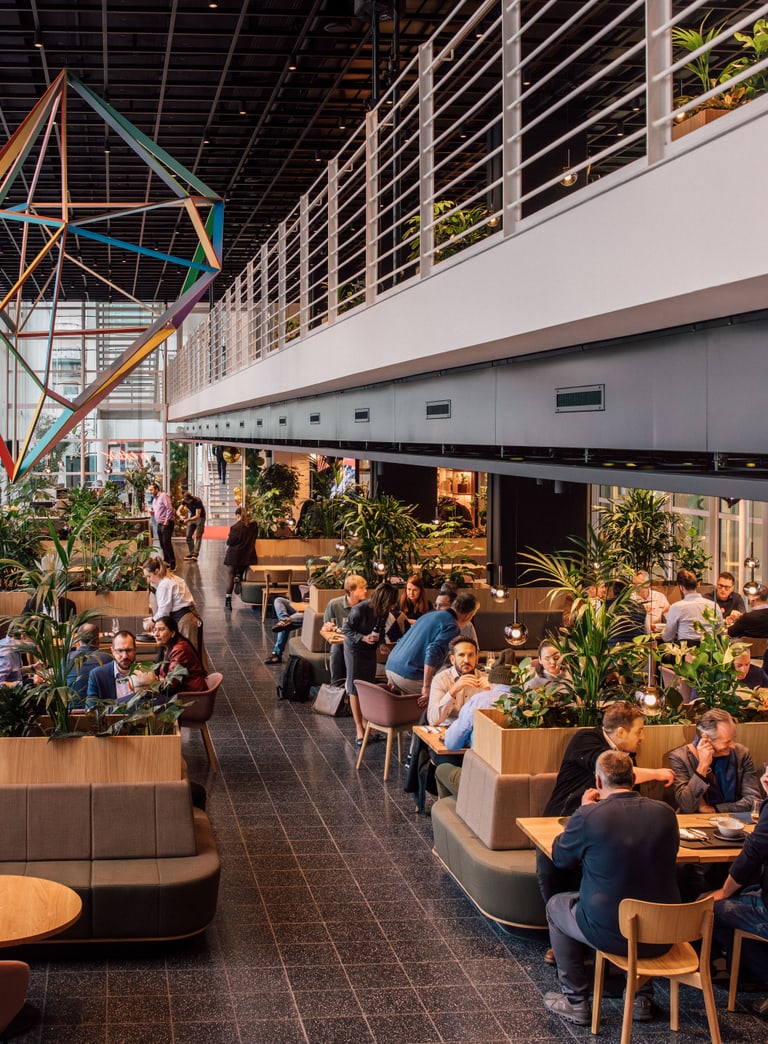 Geschäftsleute in modernem Café mit geometrischem Kunstwerk und Pflanzen.