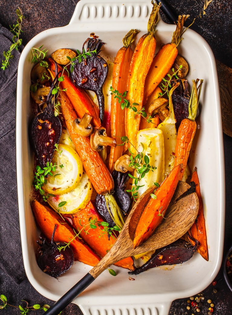 Gebackenes Wurzelgemüse in einer Auflaufform mit Holzlöffel.