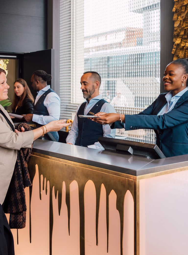 Hotelrezeption mit Personal und Gästen beim Einchecken.