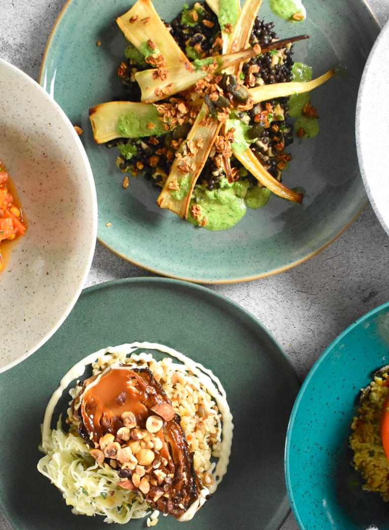 Verschiedene Bowls auf farbigen Tellern mit farbigen Gerichten von oben fotografiert und weissem Untergrund