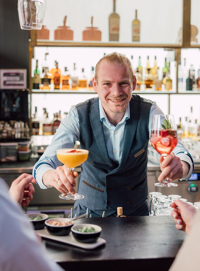 Barmann bietet Cocktails an Gäste an einer Bar an.