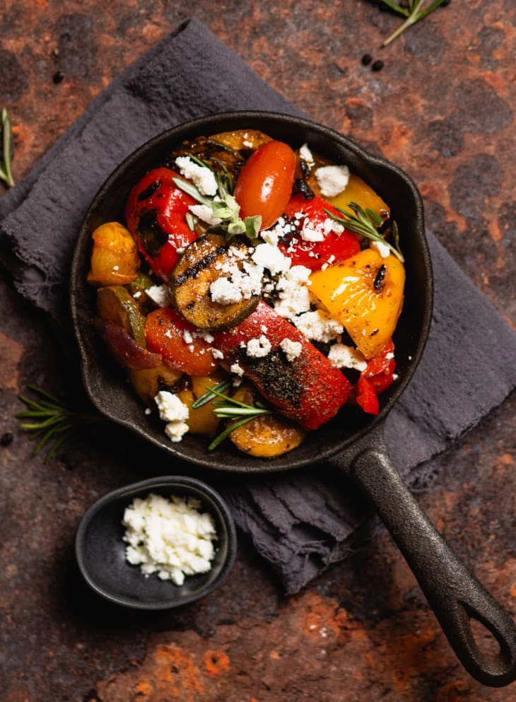 Gemüsepfanne mit Feta auf dunklem Untergrund.