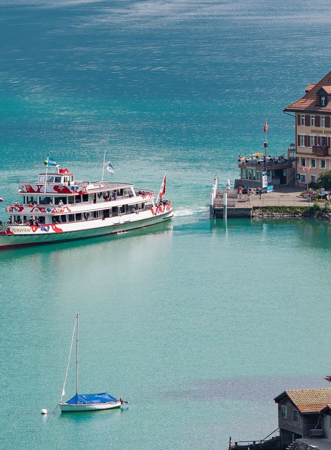 Ein Schiff fährt bei sonnigem Wetter vom Hafen weg auf dem Brienzersee.