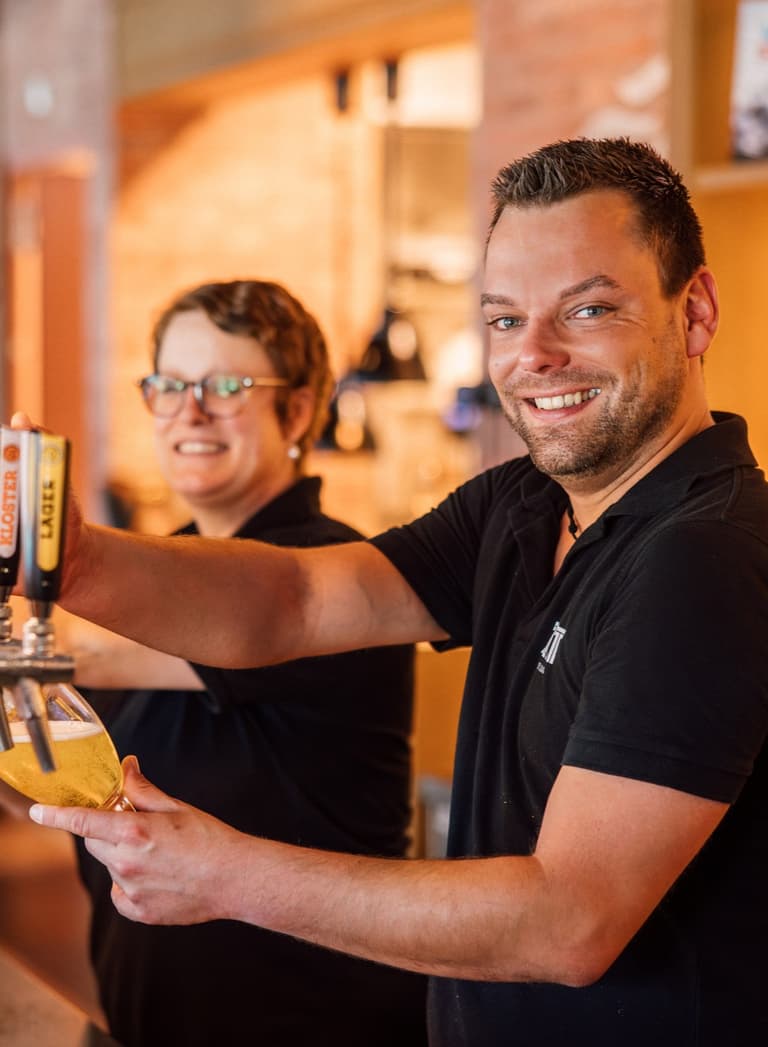 Mann und Frau zapfen Bier an der Theke.