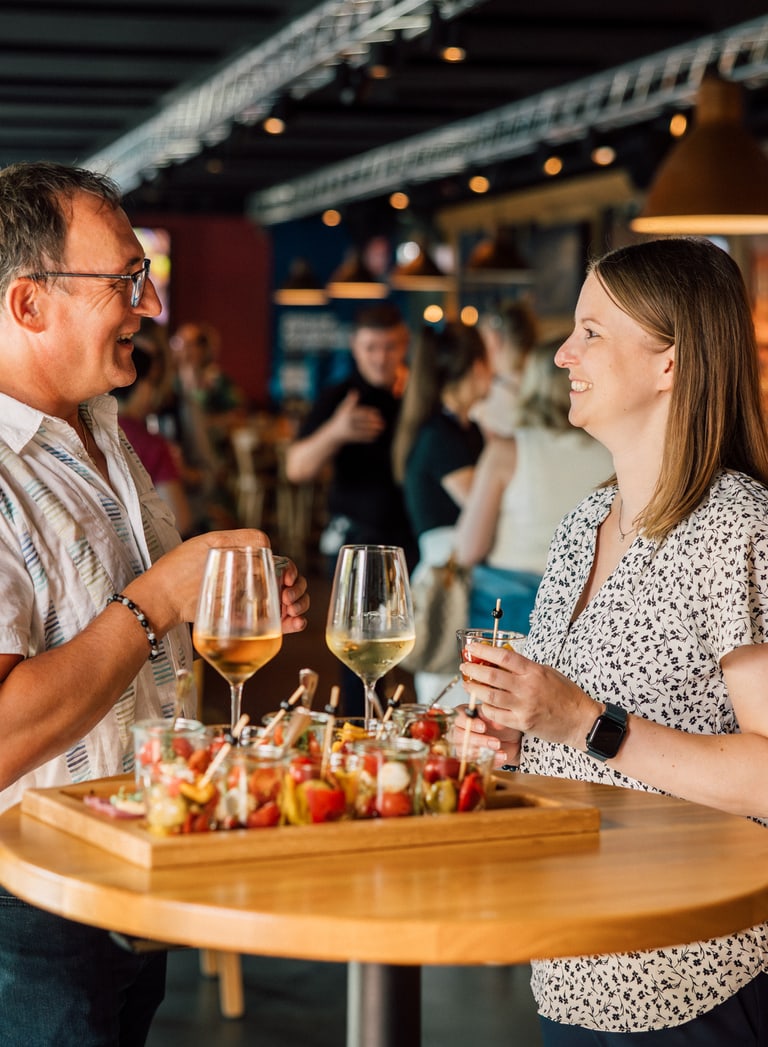 Zwei Personen unterhalten sich in einer Bar bei Getränken und Snacks.