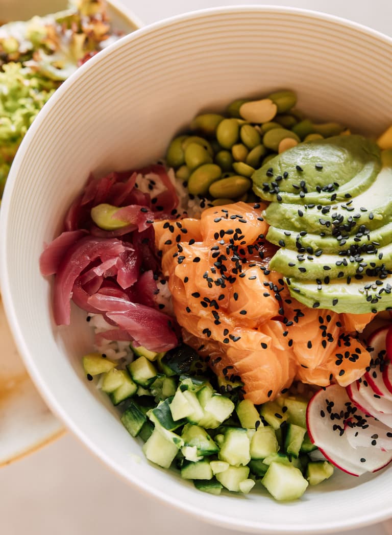 Poke Bowl mit Lachs, Avocado, Radieschen und Gemüse.