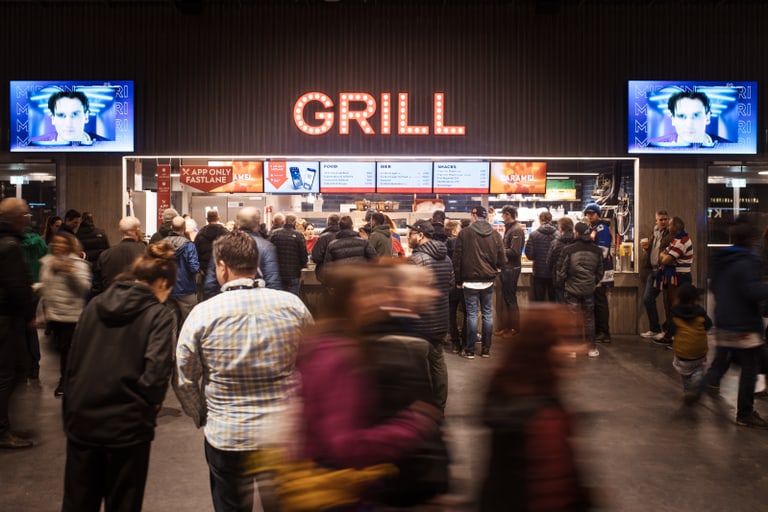 Belebte Szene vor einer Essenstation im Stadion an einem Eishockey Match in der Swiss Life Arena in Altstetten Zürich, wo die Fans auf ih Essen warten.