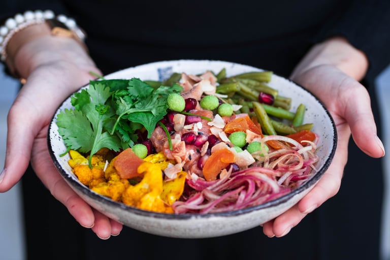 Eine Frau hält eine Bowl mit gesunden und frischen Zutaten in den Händen.