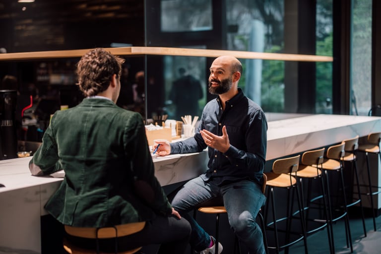 Zwei Männer unterhalten sich in einer modernen Café-Bar.