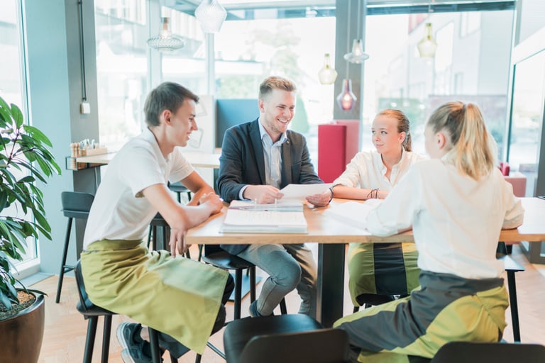 Gruppenbild Lernende mit Berufsbildner an einem Tisch