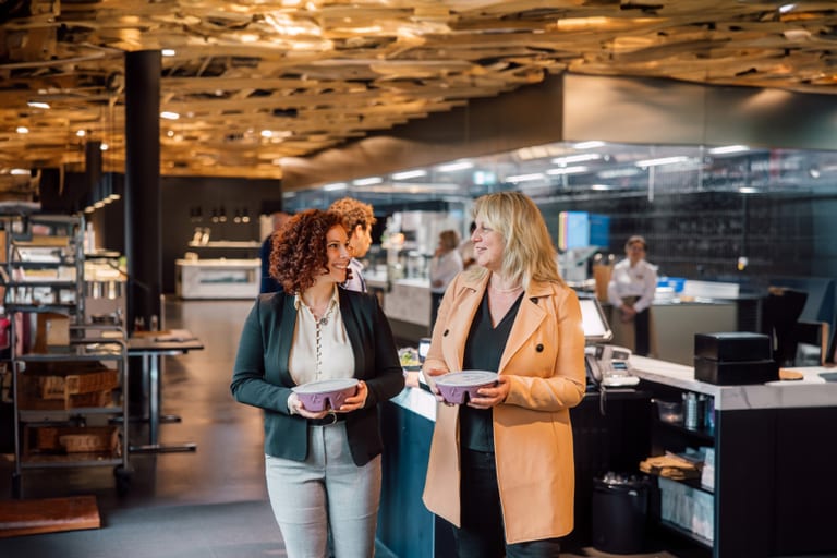 Zwei Frauen gehen in einem Restaurant mit moderner Inneneinrichtung.