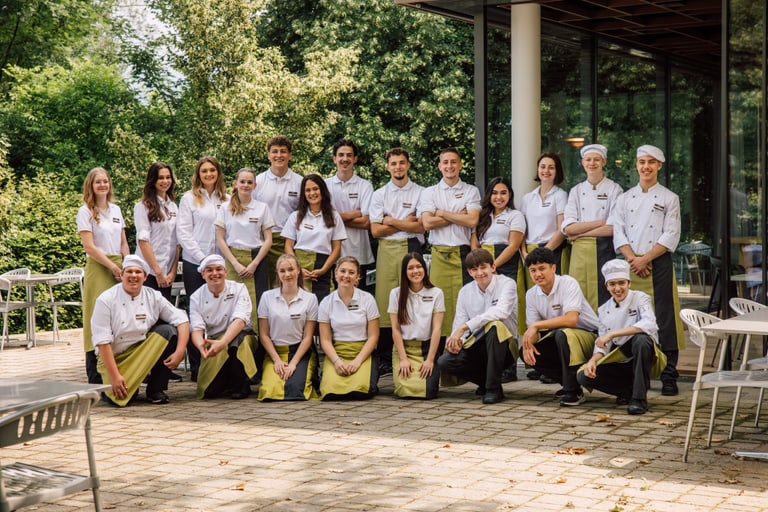 Gruppenfoto von Restaurantpersonal vor einem Gebäude im Freien.