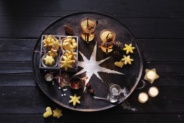 Plätzchen und Getränke auf einem Tablett mit Sternendekoration.