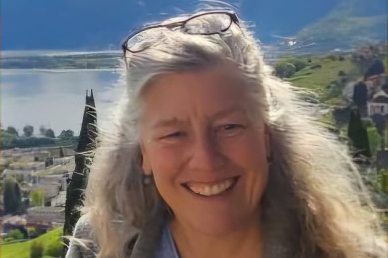 Frau lächelt vor Berg- und Seelandschaft.